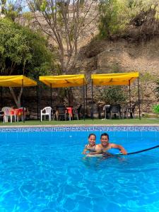 twee mensen zwemmen in een zwembad bij HUANCHACO GARDENS in Huanchaco