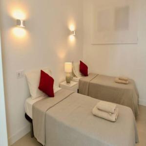 two beds with red pillows in a white room at Felmin in Portals Nous