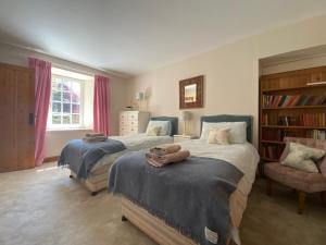 Spacious cottage - walk to Crieff في كريف: غرفة نوم بسريرين ورف كتاب