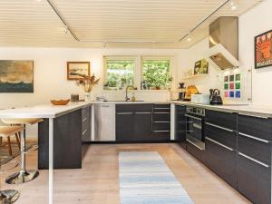 a large kitchen with black cabinets and a sink at 6 person holiday home in Ålbæk-By Traum in Ålbæk