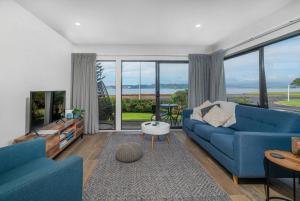a living room with a blue couch and large windows at Aqua Soleil Villas in Whitianga