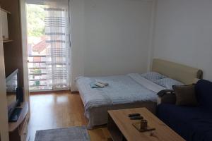 Apartman Selma - Bijelo Polje في بييلو بوليي: غرفة نوم بسرير وطاولة واريكة
