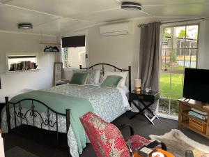 a bedroom with a bed and a tv and a window at Orange Tree Cottage - garden hideaway in Whanganui