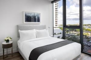 een slaapkamer met een wit bed en een groot raam bij AKA West Palm in West Palm Beach