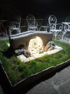 a stone fire pit in the grass next to benches at HeArt of Old Town Guesthouse in Podgorica
