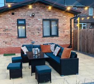 un patio con un sofá azul y una mesa en Heartland House, 7 Spacious Bedrooms Sleeps 4 plus, near NEC, JLR,BHX, en Birmingham