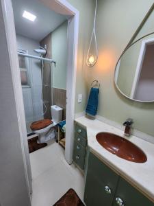 uma casa de banho com um lavatório, um WC e um espelho. em Charmoso apartamento perto da praia em Vitória