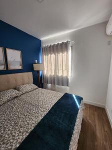um quarto com uma cama e uma parede azul em Charmoso apartamento perto da praia em Vitória