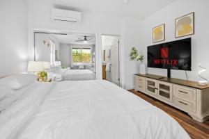 a large white bedroom with a large bed and a tv at Studio Nene - Mountains, Beaches, King Bed, Pool & Gym in Waianae