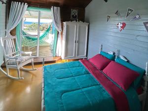 1 dormitorio con 1 cama, 1 silla y 1 ventana en Vila do Chaves - Nossa hospedagem foi matéria no G1, en Garopaba