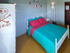 1 dormitorio con 1 cama con almohadas azules y rojas en Vila do Chaves - Nossa hospedagem foi matéria no G1, en Garopaba