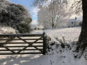 a gate covered in snow next to a driveway at Llys Onnen - North Wales Holiday Cottage in Mold