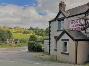 a building with arose and arousal sign next to a road at Llys Onnen - North Wales Holiday Cottage in Mold