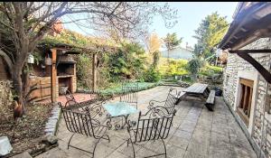 eine Terrasse mit Stühlen, einem Tisch und einer Bank in der Unterkunft La Maison bleue in Varzy