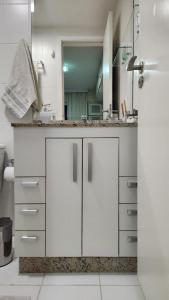 a white bathroom with a sink and a mirror at Apartamento por temporada RJ próximo ao Riocentro, Parque Olímpico e Jeunesse Arena in Rio de Janeiro
