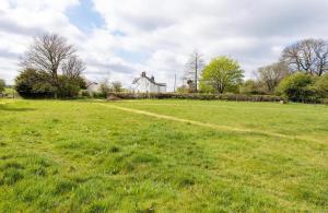 a field of green grass with a white house in the background at Llys Onnen - North Wales Holiday Cottage in Mold +34 photos