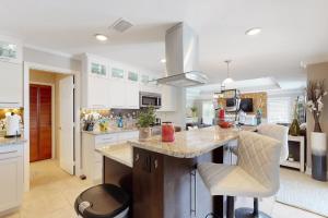 eine Küche mit weißen Schränken und eine Insel mit Barhockern in der Unterkunft Blue Sunset in Bonita Springs