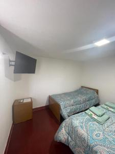 Habitación con 2 camas y TV en la pared. en Monoambiente El Sosiego en Alta Gracia