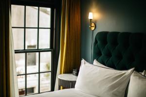 a bedroom with a bed and a large window at Hotel Emeline in Charleston