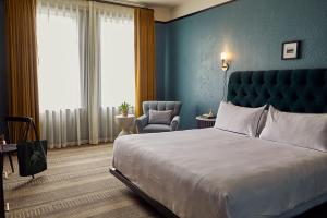 a bedroom with a large bed and a chair at Hotel Emeline in Charleston