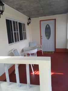 een veranda met stoelen, een tafel en een deur bij Alexander's Apartment in Carriacou