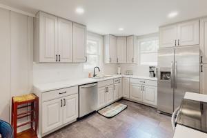 uma cozinha com armários brancos e um frigorífico de aço inoxidável em Pine Whiff Beach House em Annapolis