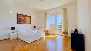 a white bedroom with a bed and a large window at Apartment Reful in Kraljevica