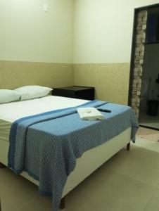a bedroom with a bed with a blue blanket at Hotel Vitalle in Juiz de Fora