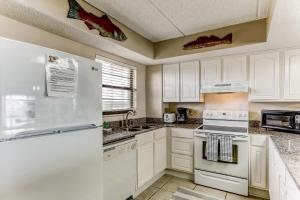 a kitchen with white cabinets and a white refrigerator at Amelia The Sea - 558 ASea in Fernandina Beach