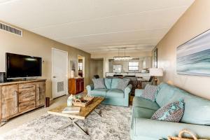 a living room with two blue couches and a flat screen tv at Amelia The Sea - 558 ASea in Fernandina Beach