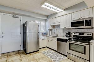 a kitchen with white cabinets and a stainless steel refrigerator at Steps to Oceanside Condo in Amelia Island