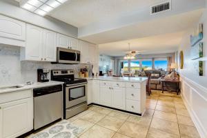 a kitchen with white cabinets and a view of a living room at Steps to Oceanside Condo in Amelia Island