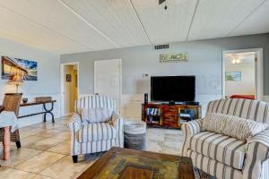 a living room with two chairs and a flat screen tv at Steps to Oceanside Condo in Amelia Island