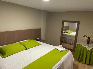 1 dormitorio con 1 cama con sábanas verdes y espejo en Terraza Dreams, en Quito