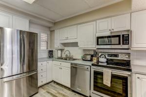una cocina con armarios blancos y electrodomésticos de acero inoxidable en Oceanview Upper Unit Condo en Amelia Island