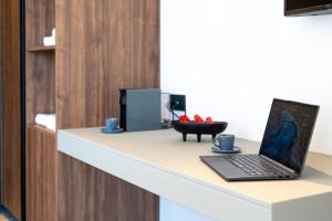 a laptop sitting on a desk with two blue cups at El Greco in Igoumenitsa