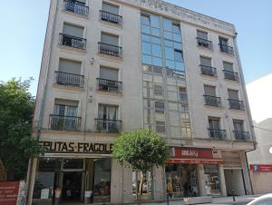 a tall building on a city street with a store at Piso Alerín in Silleda