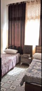 a bedroom with two beds and a window with curtains at Jawal Hotel in Amman