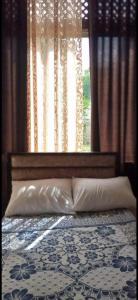 ein Bett mit zwei Kissen und ein Fenster mit Vorhängen in der Unterkunft Jawal Hotel in Amman
