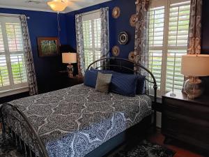 a bedroom with a bed with blue walls and windows at Blue Ruby at Grice-Fearing B&B in Elizabeth City