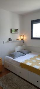 - une chambre avec un grand lit blanc et une fenêtre dans l'établissement Chambre chaleureuse avec une vue dégagée, à La Frette-sur-Seine