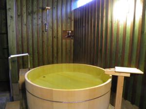 a bath tub in a bathroom with a wooden wall at 旬樹庵　菊水 in Chikuma