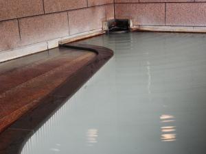 a pool of water next to a brick wall at 旬樹庵　菊水 in Chikuma
