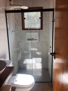 La salle de bains est pourvue de toilettes et d'une douche en verre. dans l'établissement Chalé Campestre, à Gonçalves