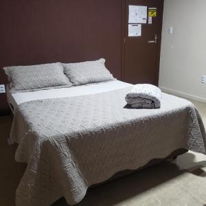 a bed with a blanket and pillows on it at Hospedagem Costa BNU - Q1 in Blumenau