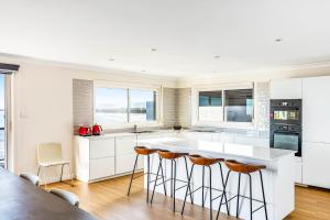 a kitchen with white cabinets and a large island with bar stools at Amaroo in Gerroa