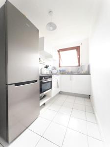 a white kitchen with a stainless steel refrigerator at KayChouchou- Appart cosy au cœur de Fort-de-France in Fort-de-France