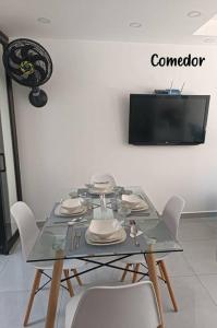 a table with white chairs and a television on a wall at Ricaurte, Cundinamarca in Girardot