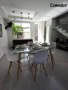 a dining room with a glass table and white chairs at Ricaurte, Cundinamarca in Girardot