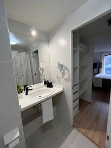 a white bathroom with a sink and a bed at Departamento Barrio Lastarria in Santiago